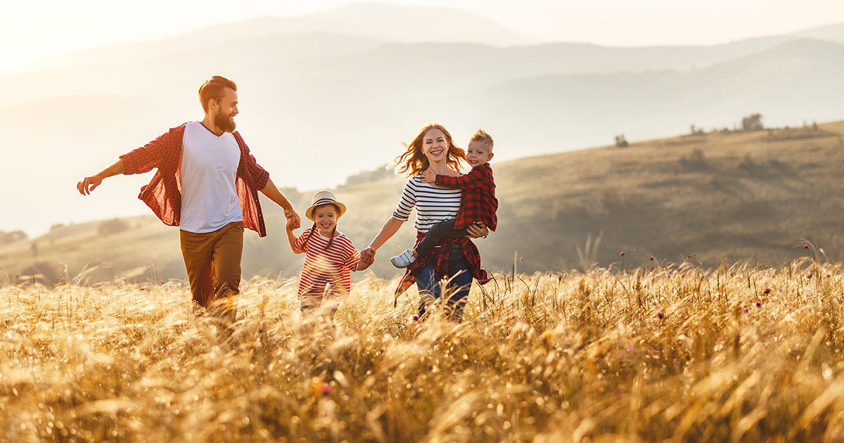 famille 2 parents 2 enfants main dans la main, marche dans un pré