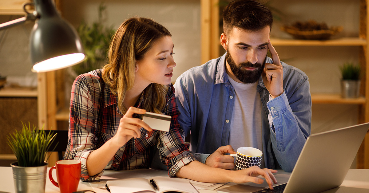 couple tenant une carte de crédit payant ses factures par ordinateur