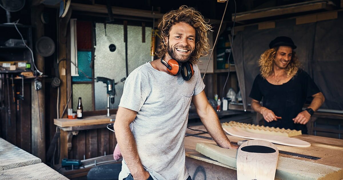 homme blond souriant travaille sur une planche de surf