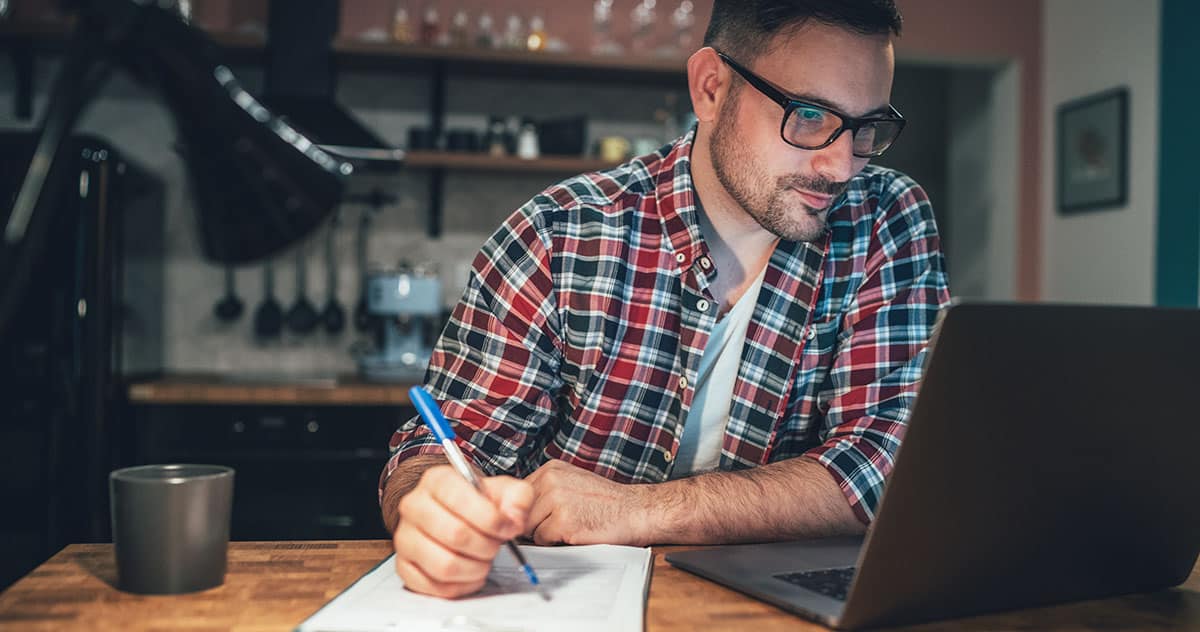 homme trentenaire. Cheveux brun, lunette. Devant un ordinateur, prend des notes. ambiance chaleureuse